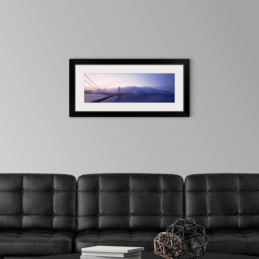 A modern room featuring Panoramic photograph of overpass crossing ocean and disappearing into fog.