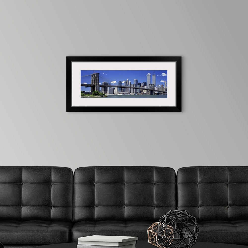 A modern room featuring The World Trade Center buildings rise over the city skyline near the large suspension bridge in t...
