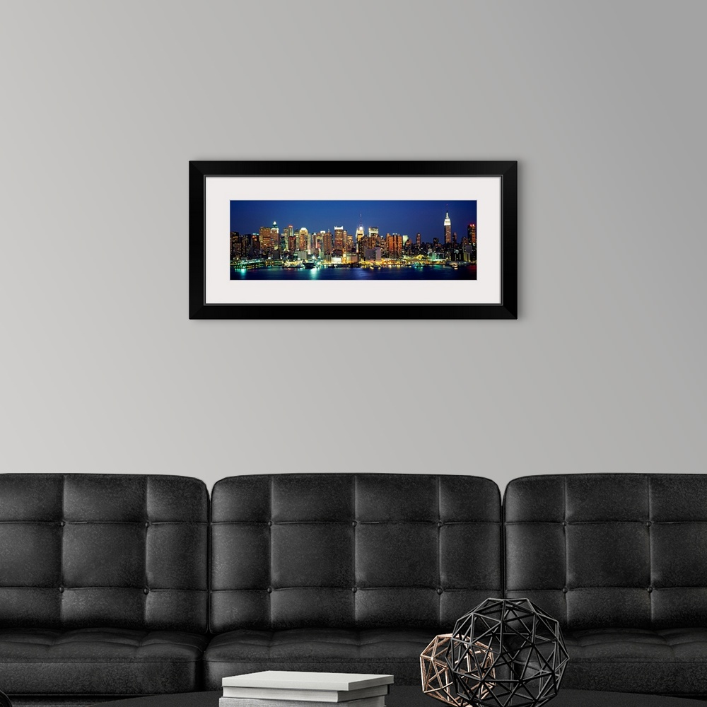 A modern room featuring A panoramic photograph of the Manhattan shore and skyscrapers illuminated at night.