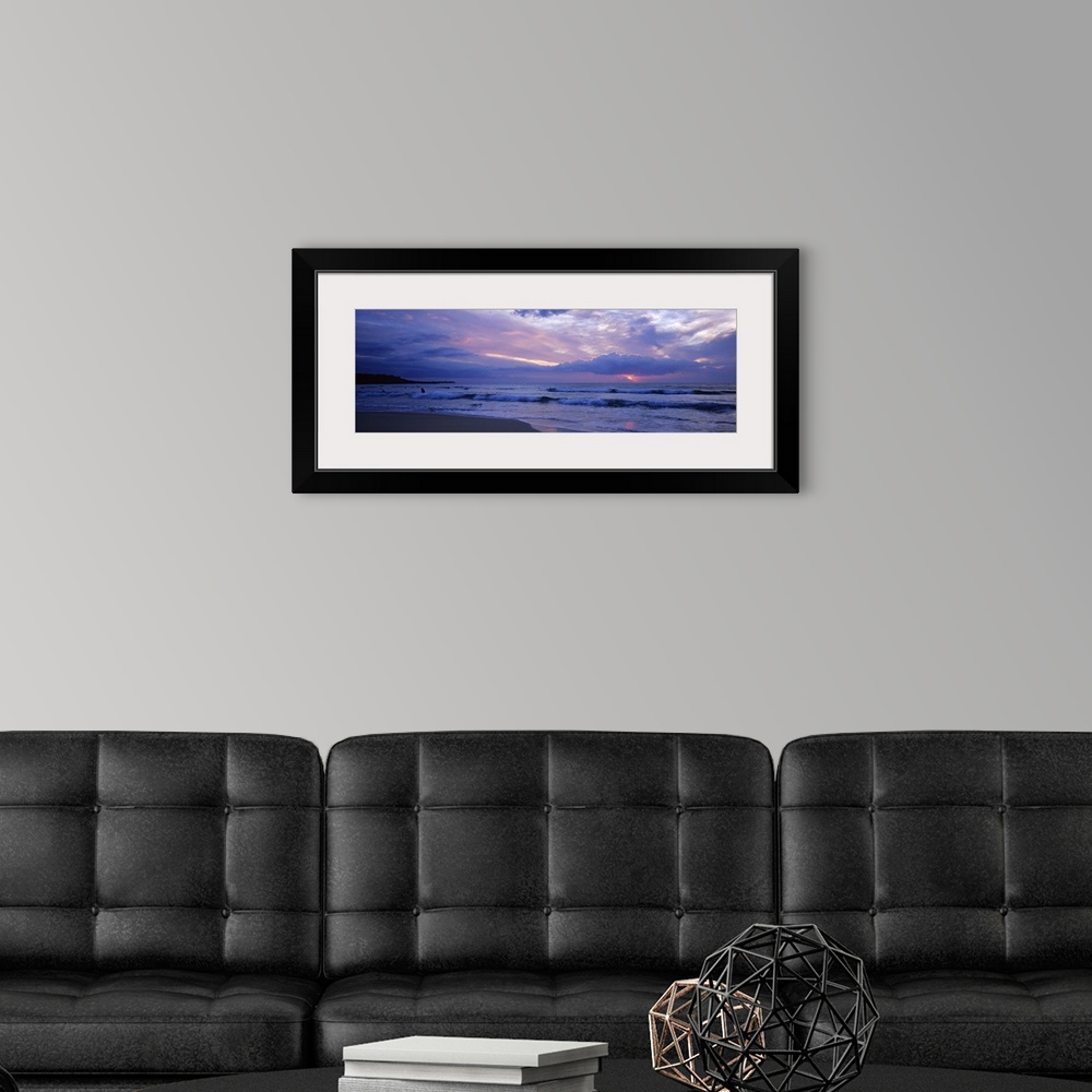 A modern room featuring This big picture is a panoramic photograph of the ocean surf sweeping over the shore. The sun fil...