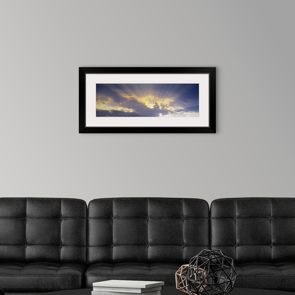 A modern room featuring A horizontal canvas photo of sun rays shining through clouds.