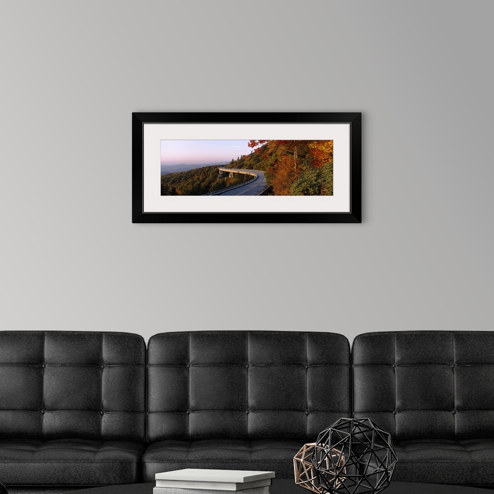 A modern room featuring Panoramic photograph of winding mountain road with tree tops below it and mountain silhouette in ...