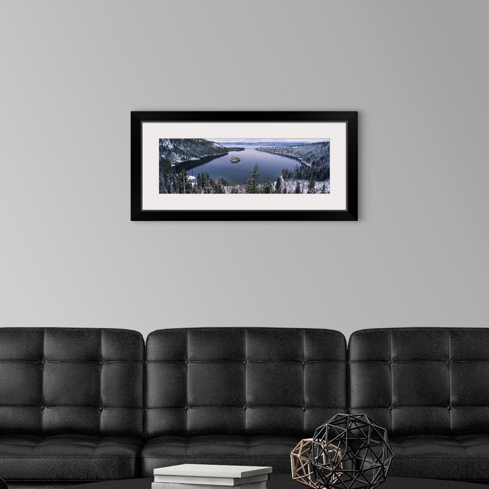 A modern room featuring Panoramic photograph of inlet surrounded by snow covered forest under a cloudy sky.