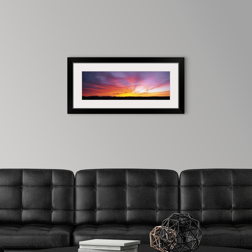 A modern room featuring The strip of land at the bottom of this piece is silhouetted by the beautiful sunset that has dip...