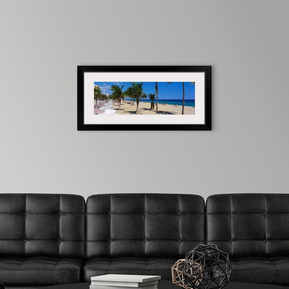 A modern room featuring Panoramic photograph showcases a lively beach scene scattered with people within Florida that has...