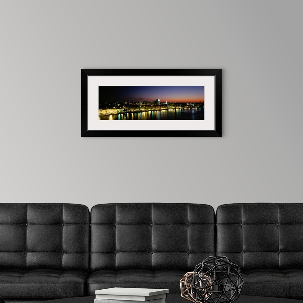A modern room featuring Panoramic photograph of lit up skyline and waterfront at sunset under a colorful sky.