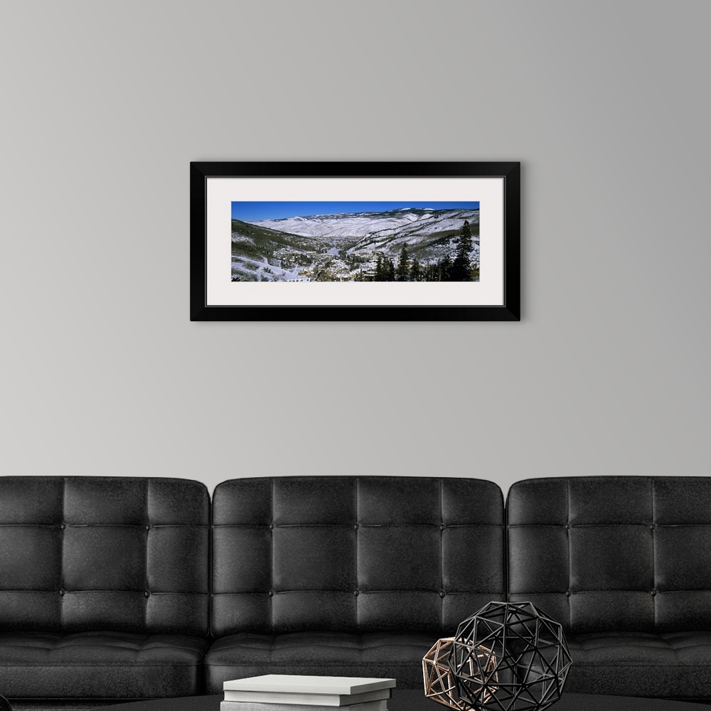 A modern room featuring An aerial photograph taken of ski resort planted in the middle of large mountains covered with sn...