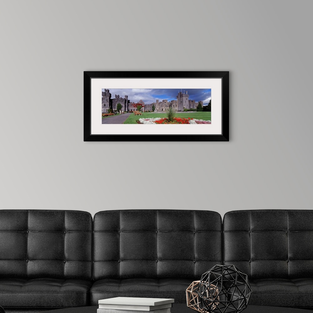 A modern room featuring Panoramic photograph taken of an immense castle that has lush green grass in the front yard fille...
