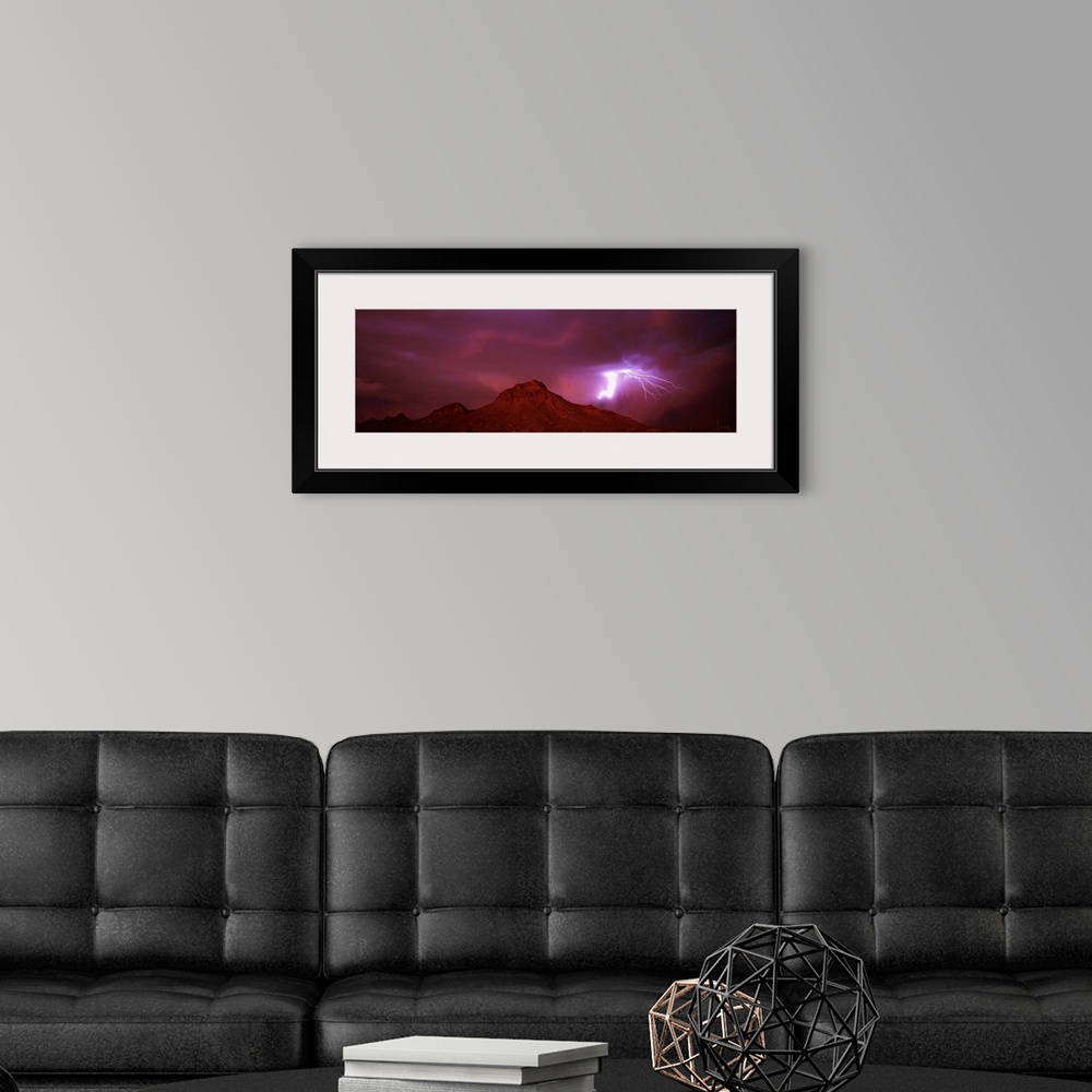 A modern room featuring Panoramic painting of mountain range under a dark cloudy sky with bolts of lightning.