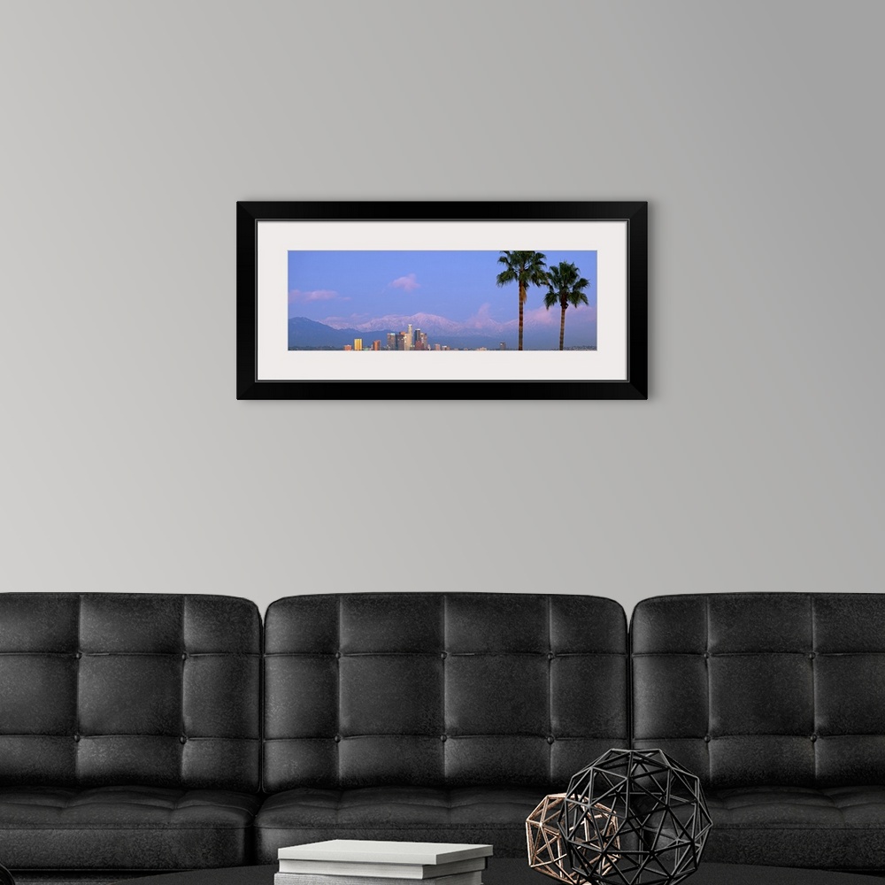 A modern room featuring Panoramic photograph of skyline and palm trees under a cloudy sky with mountain silhouettes in th...