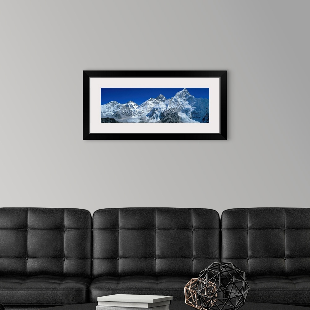 A modern room featuring Giant, wide angle landscape photograph of snow covered Himalaya Mountains against a blue sky, inc...