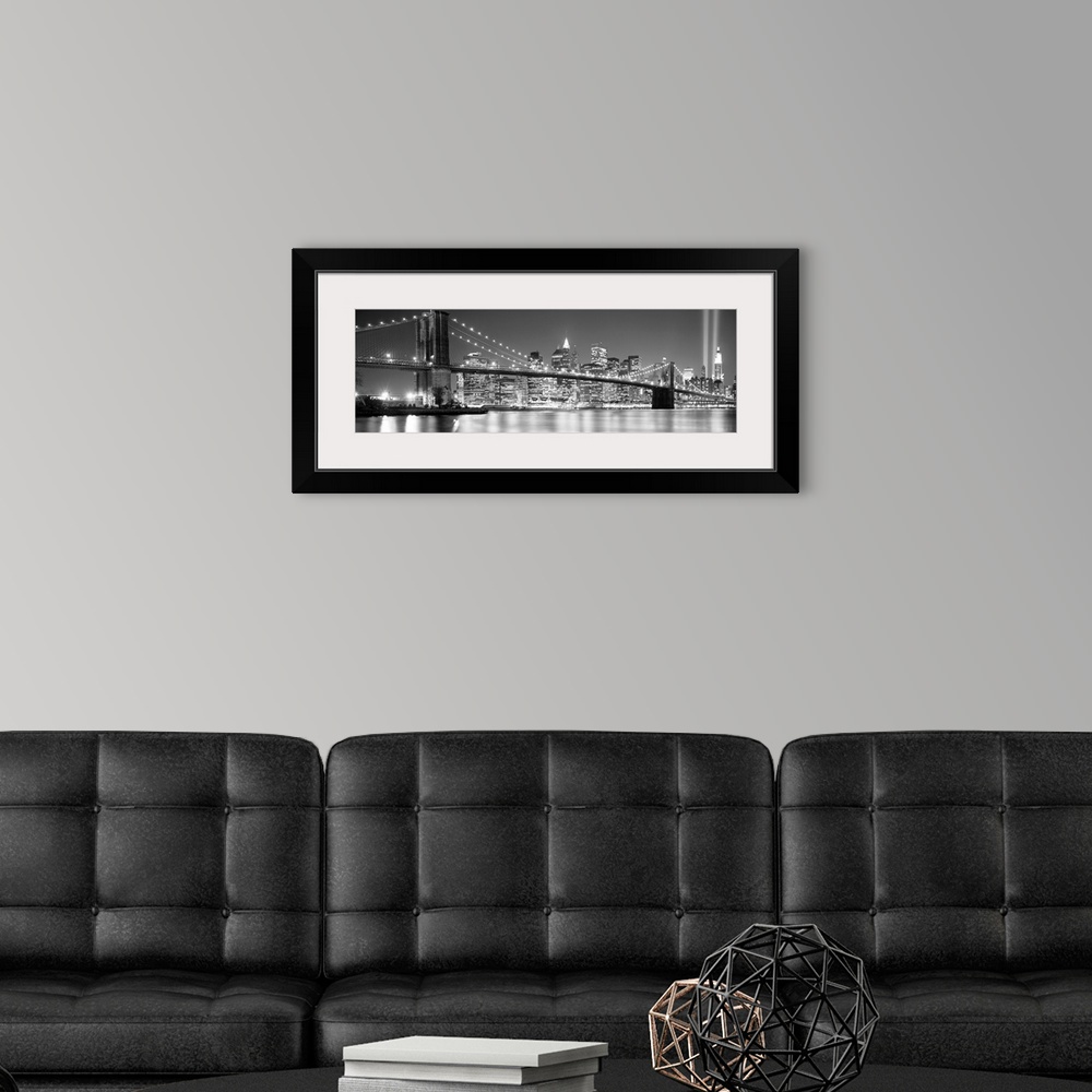 A modern room featuring A panoramic landscape photo taken after 2001 of Manhattan and Brooklyn Bridge shining bright over...