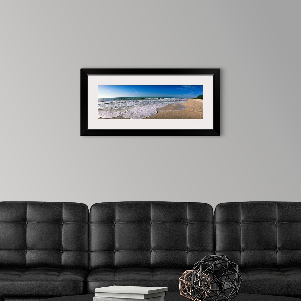 A modern room featuring Panoramic photograph displays waves from the Gulf of Mexico as they gently break onto a sandy bea...