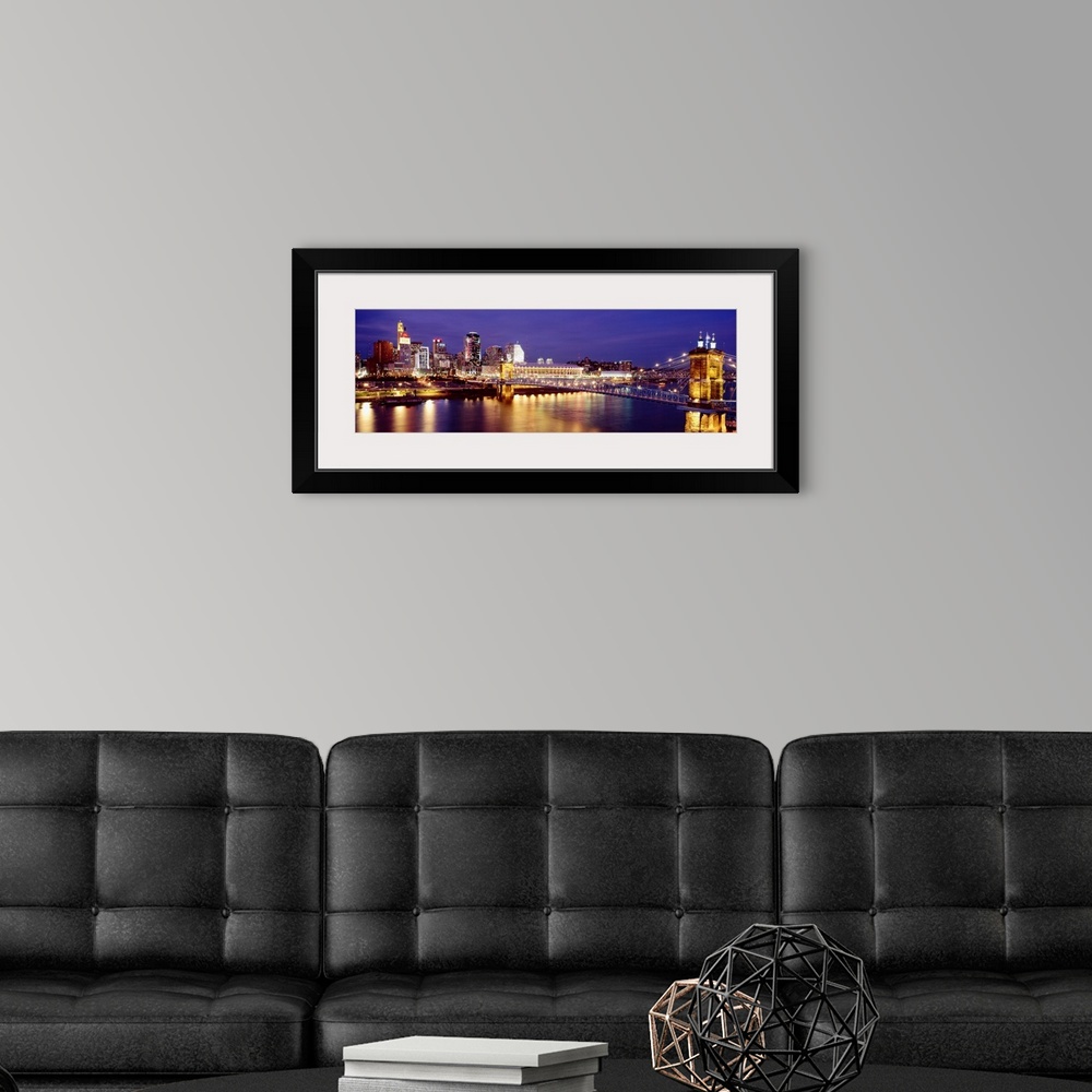 A modern room featuring Horizontal photograph on a large canvas of the night lights of Cincinnati's downtown waterfront a...