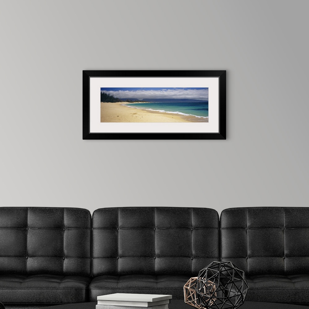 A modern room featuring Wide angle photograph on a large wall hanging of clear blue waters along the beach in Maui, Hawai...
