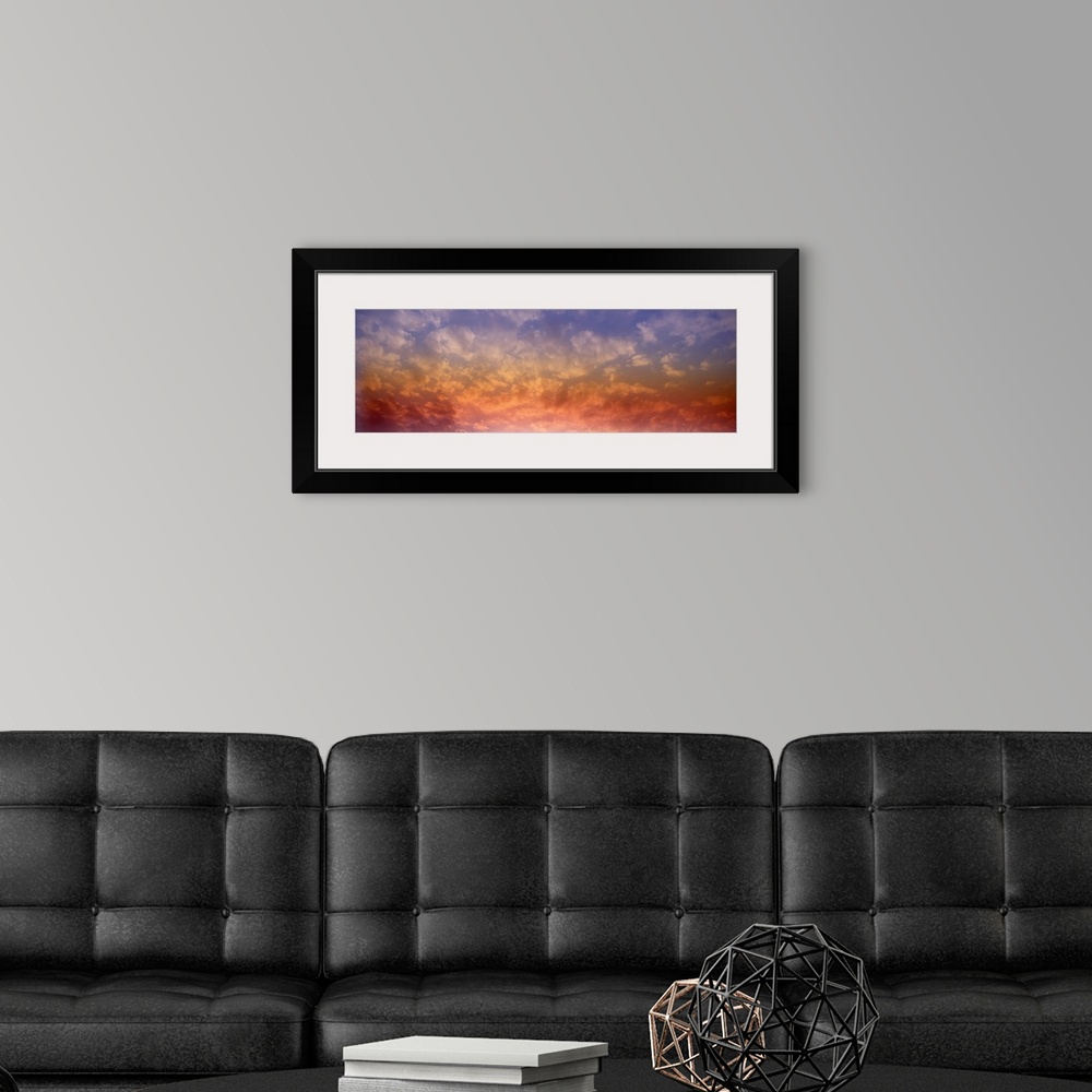 A modern room featuring Panoramic photograph of colorful clouds illuminated by the sun.