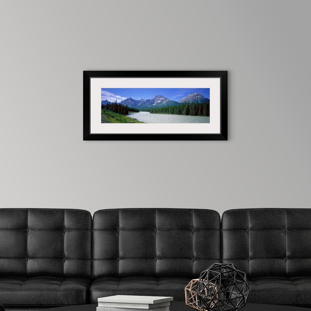 A modern room featuring Panoramic photograph of river winding through forest with mountain range in the distance under a ...