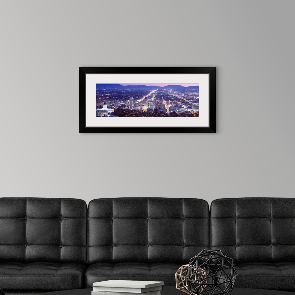 A modern room featuring Panoramic aerial photograph of city lit up at  night with mountain silhouettes in the distance.