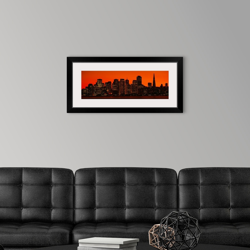 A modern room featuring The skyline in San Francisco is pictured in wide angle view with a warm background silhouetting t...