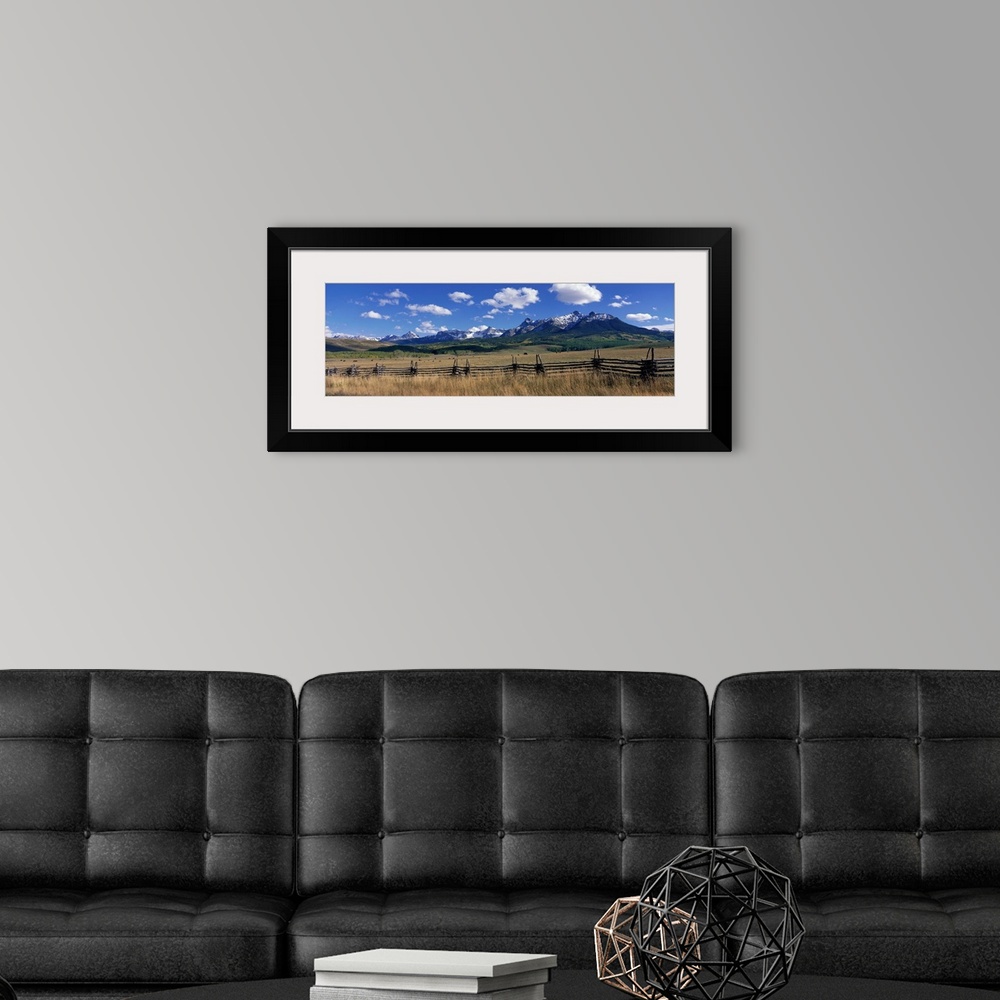 A modern room featuring Horizontal, large photograph of a distant mountain range beneath a bright blue sky, cattle grazin...
