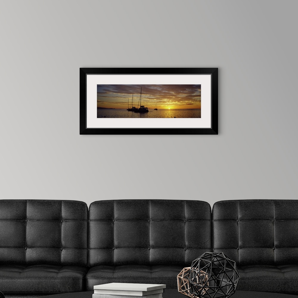 A modern room featuring Panoramic photograph on a big wall hanging of several silhouetted sailboats, floating on calm wat...