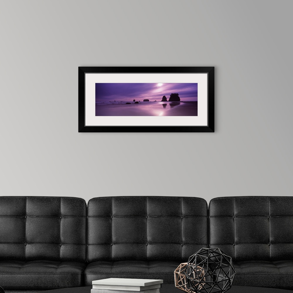 A modern room featuring Panoramic photograph taken from a beach with silhouettes of rock formations in the distance as th...