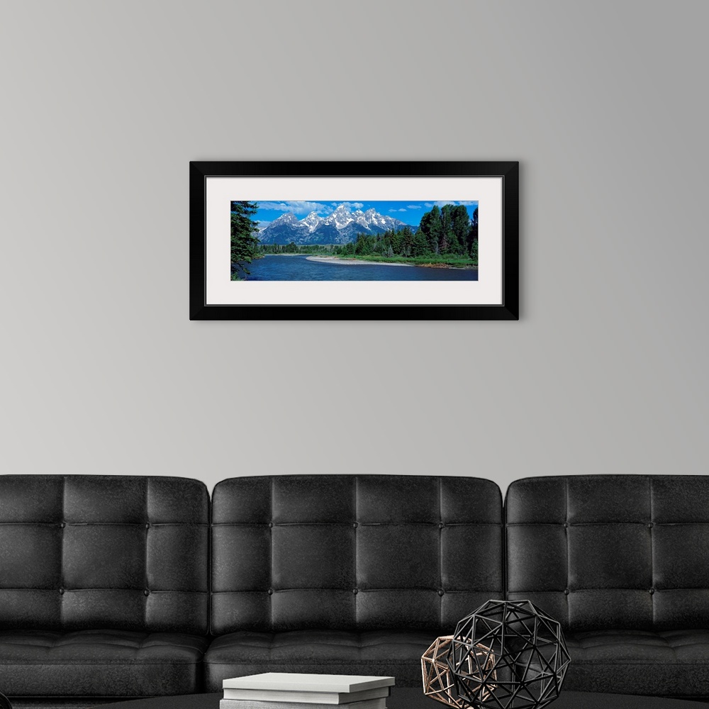 A modern room featuring Panoramic photo of rugged mountains in the background of a wide river cutting through the landsca...