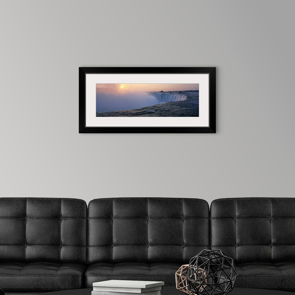 A modern room featuring Big canvas print of water rushing down Niagara Falls with the sun rising in the distance.