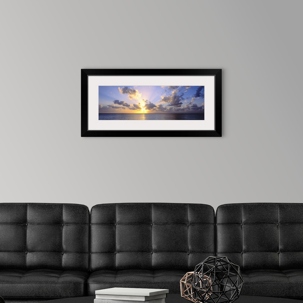 A modern room featuring Giant panoramic photograph of the sun about to set in the distance from the perspective of a beac...