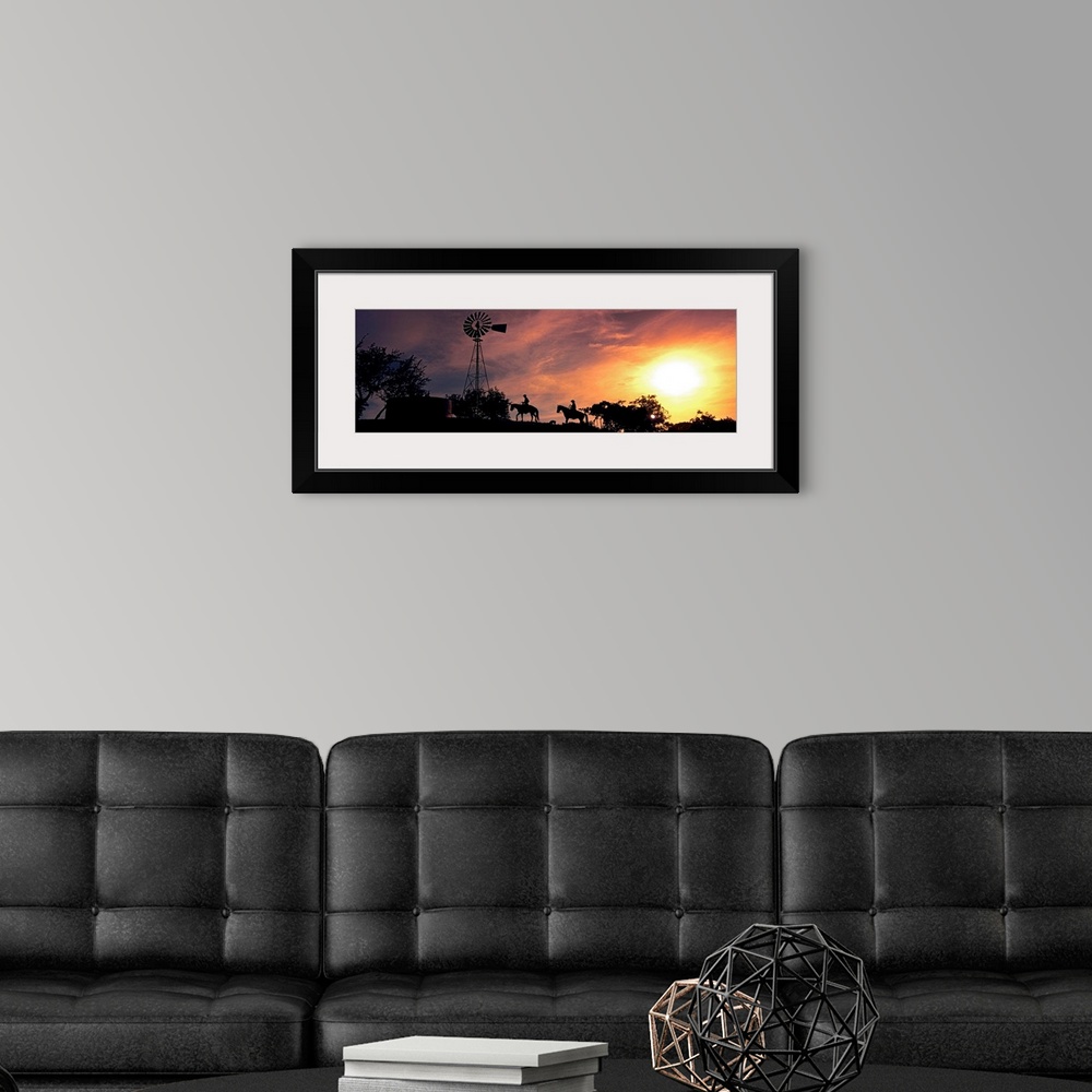 A modern room featuring This panoramic photograph depicts an evening moment on ranch hill side as horseback riders pass b...