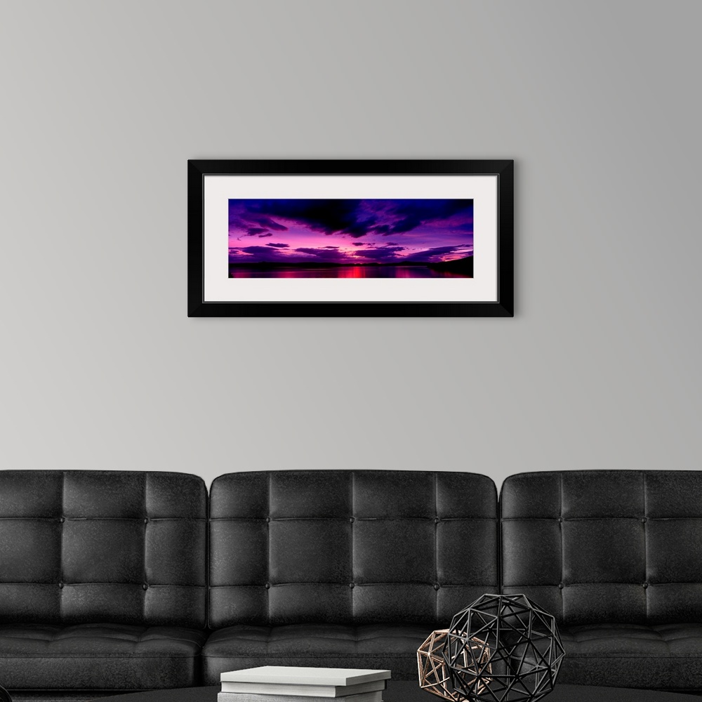 A modern room featuring A panoramic photograph of clouds in the sky and light reflecting off water in the twilight colors.