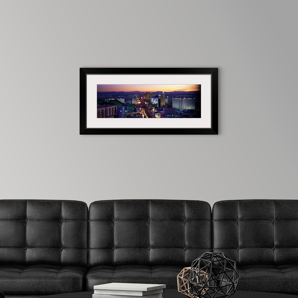 A modern room featuring Panoramic photograph of ""Sin City"" skyline at sunset with buildings lit up and mountains in the...