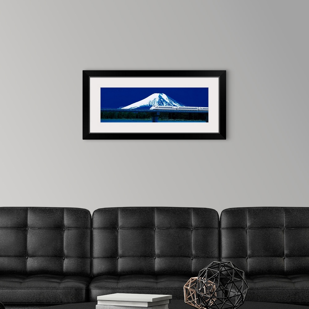 A modern room featuring Panoramic photo on canvas of a train going across a bridge above water with a snowy mountain the ...