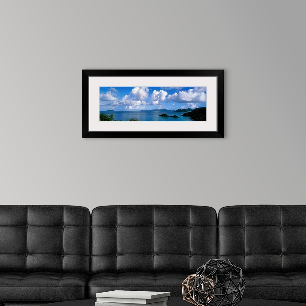 A modern room featuring Panoramic photograph of ocean sprinkled with small grass covered islands under a cloudy sky.