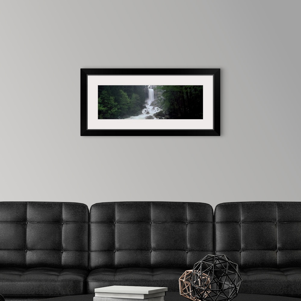 A modern room featuring Panoramic photograph of waterfall flowing into a rocky stream lined with thick dense forest.