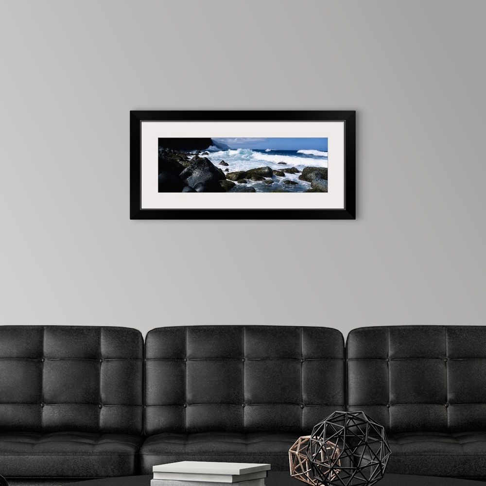 A modern room featuring Panoramic photograph on a big canvas of waves crashing onto large rocks along the coast of Na Pal...