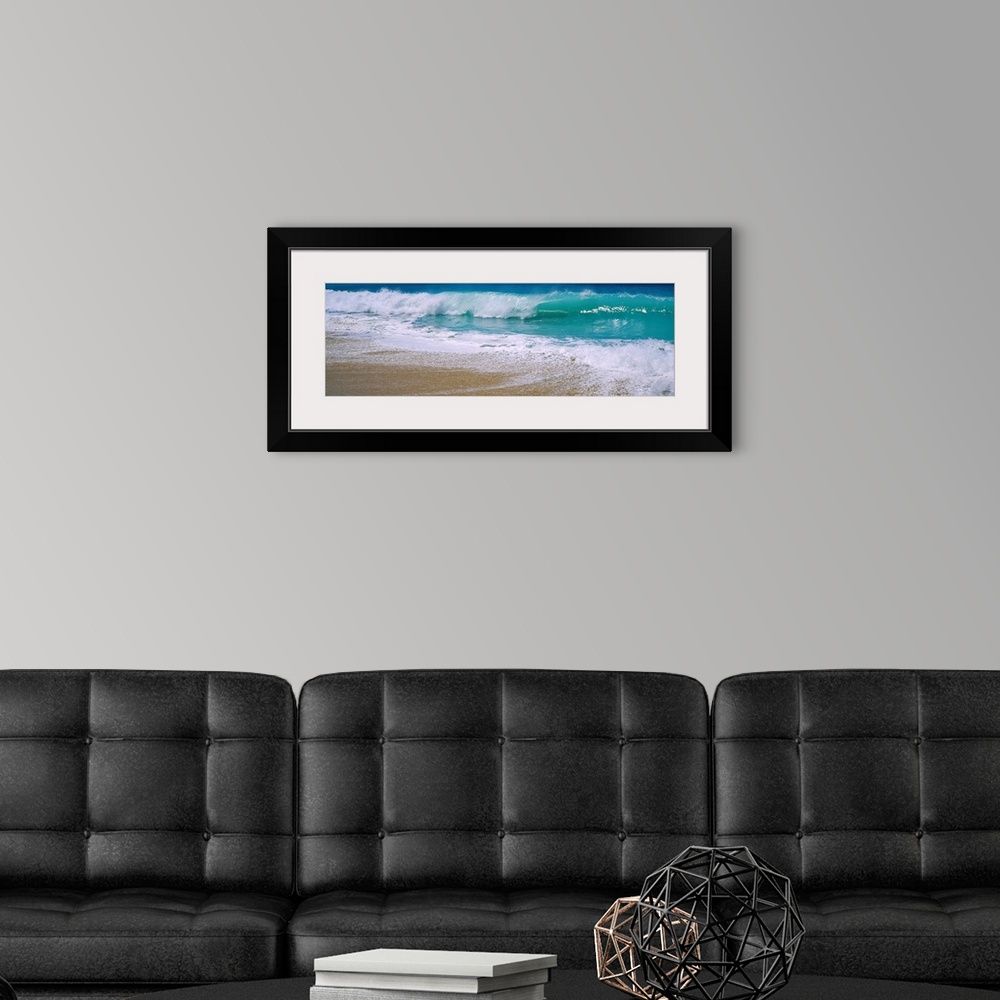 A modern room featuring Panoramic photograph of water crashing onto the sand and being swept back out to sea.