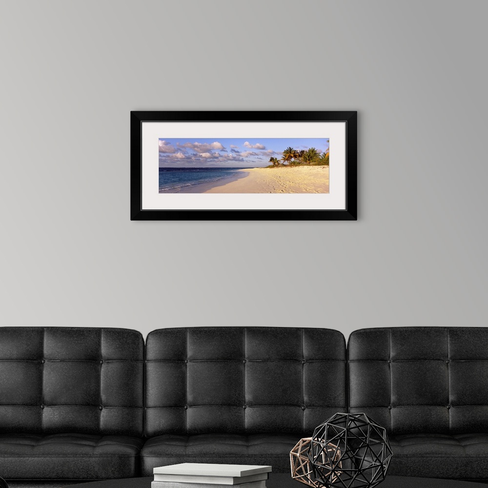 A modern room featuring Big panoramic photo of waves trickling onto the Shoal Bay Beach in Anguilla. Fooprints can be see...