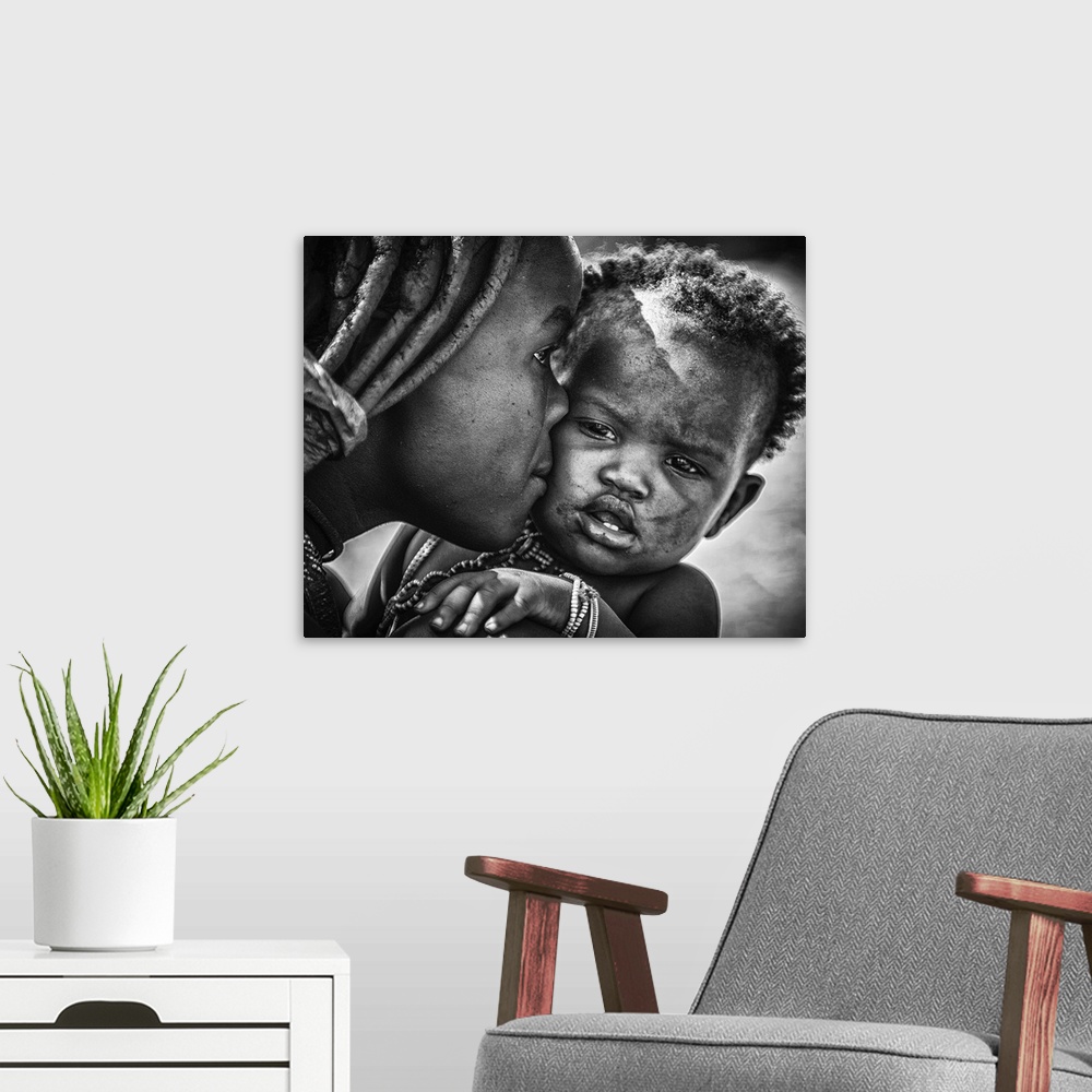 A modern room featuring A young boy pulls a funny face as his mother kisses him, Namibia.