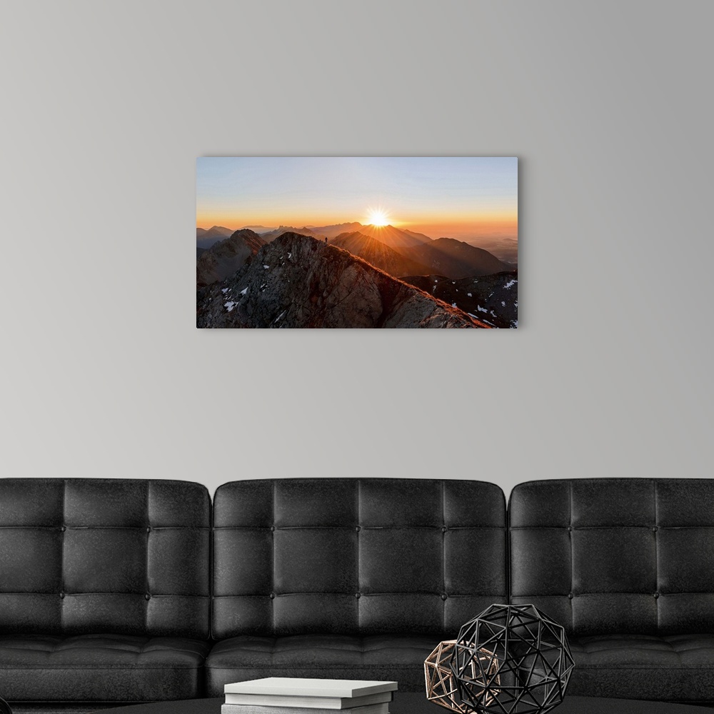 A modern room featuring A man running on the ridge of a mountain as the sun rises over the peaks, Stol, Slovenia.