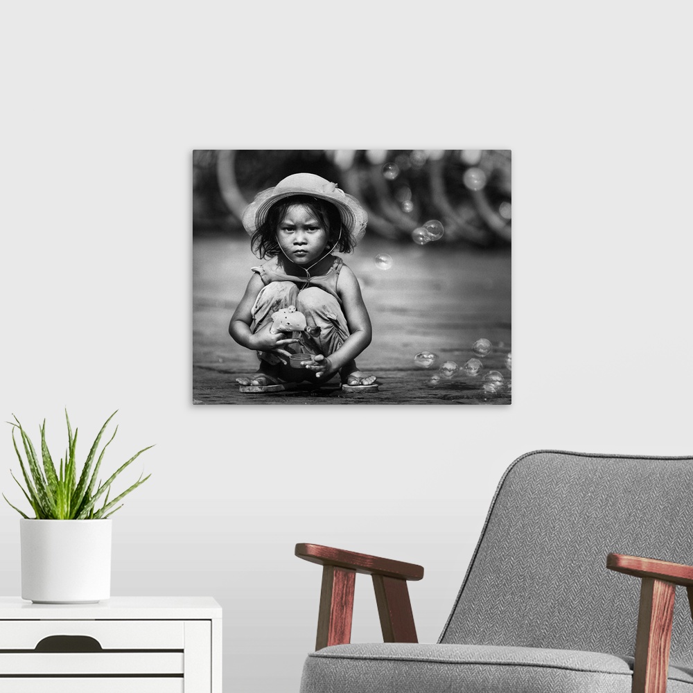 A modern room featuring Portrait of a young Indonesian girl playing in the street with a bubble gun.