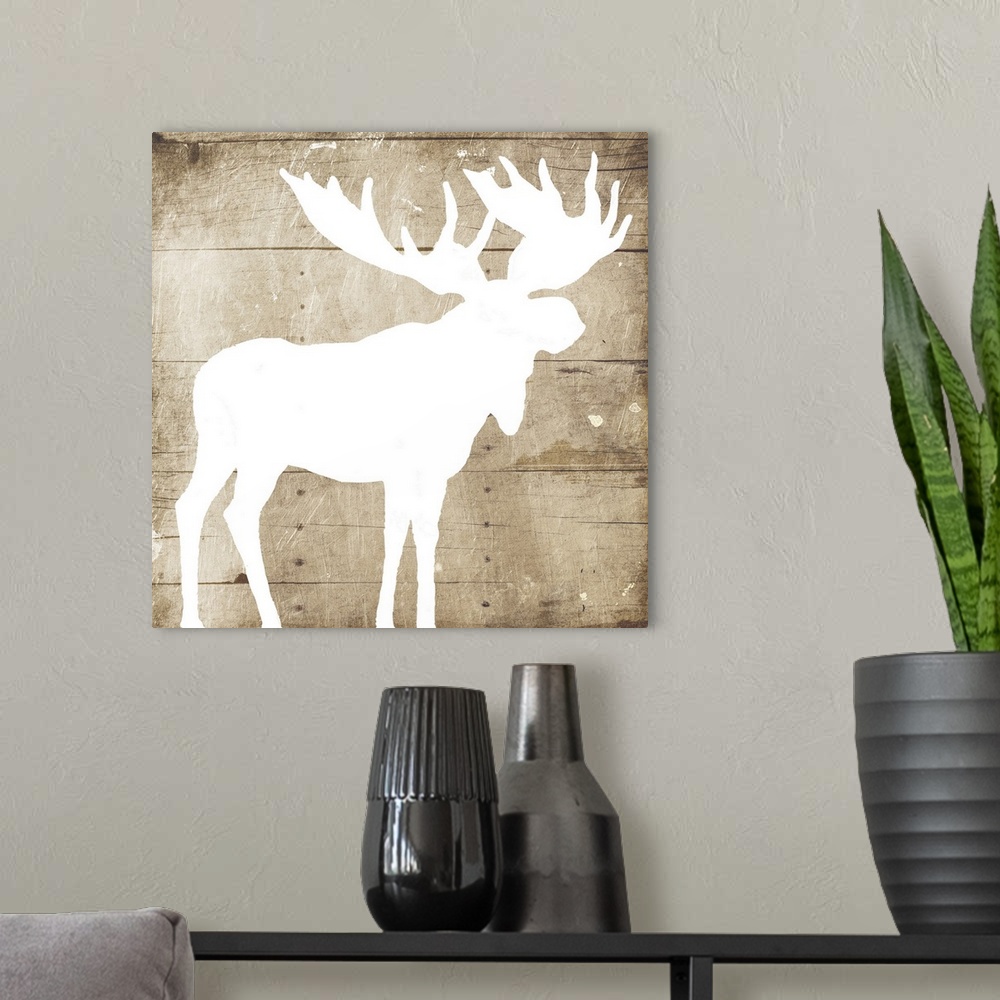 A modern room featuring A white silhouette of a moose painted on a wood background.