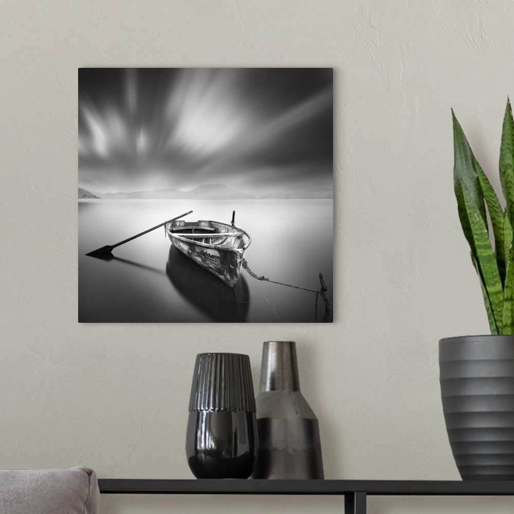 A modern room featuring An artistic black and white photograph of a lone and unattended rowboat on a still watery surface...