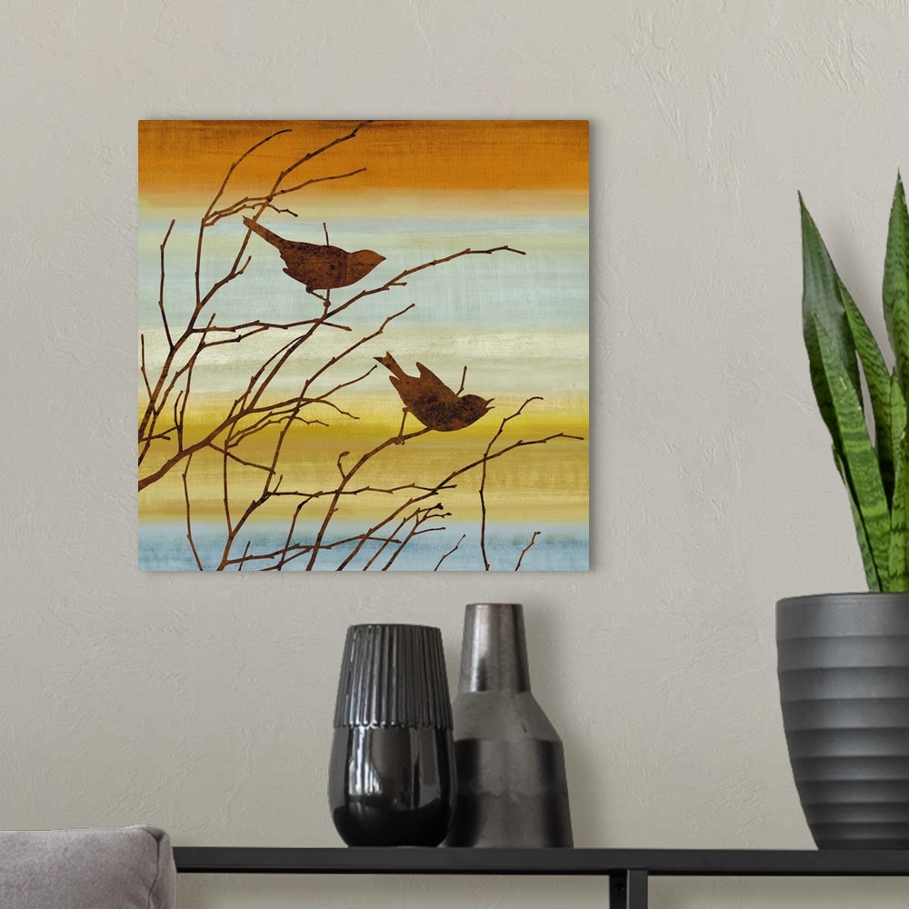A modern room featuring Square decor with silhouettes of two birds and Winter branches on a warm and colorful background.