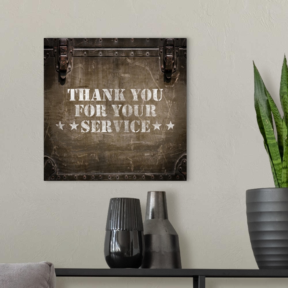 A modern room featuring "Thank You For Your Service" stenciled in white on a worn trunk.