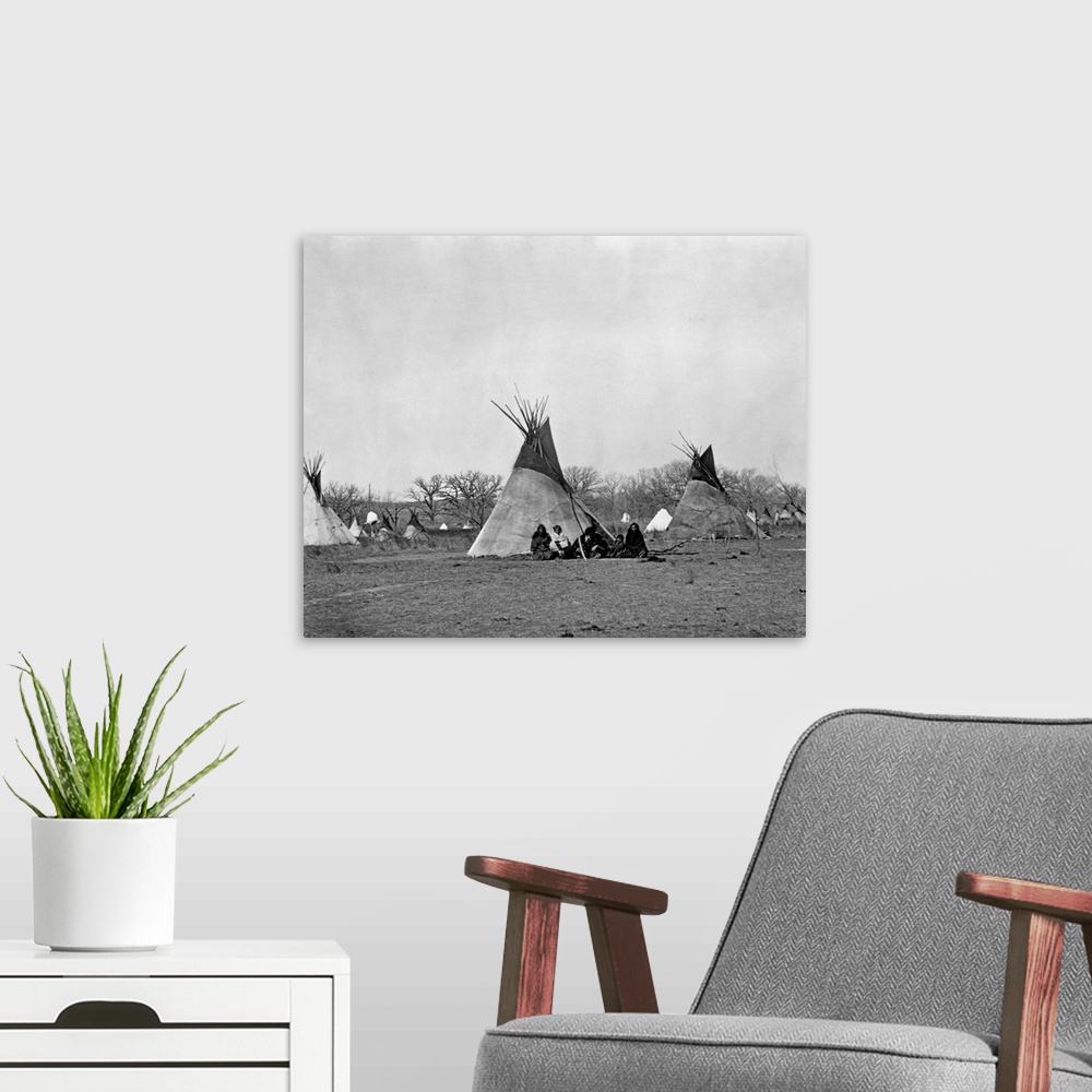 A modern room featuring A Comanche Indian family sits outside their teepee in the Iron Mountain's Camp, 1873.