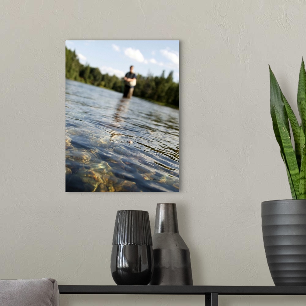 A modern room featuring A close-up of a fisherman's fly on the water as he stands in the distance fly fishing the Swan River
