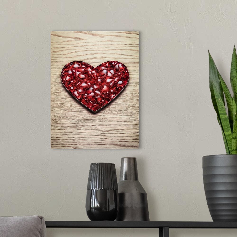 A modern room featuring A mass of plastic red hearts sit in a heart shape on a wooden background