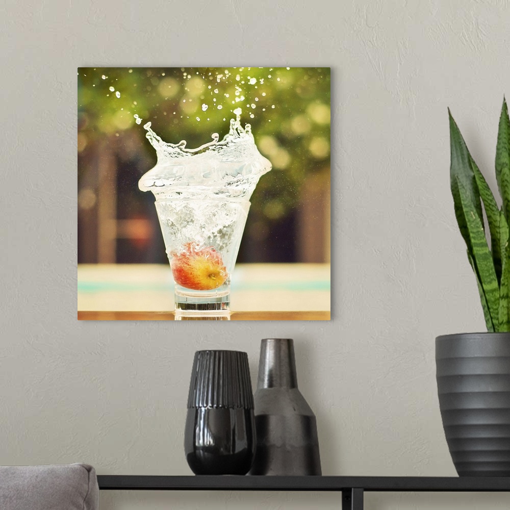 A modern room featuring Splash in glass of water with tiny apple. Fresh sensation, end of summer.