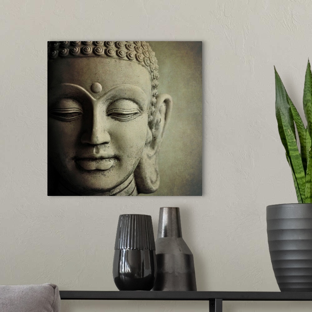 A modern room featuring Close up photo of the face of a  sculpture of Buddha, showing his downcast eyes and tight curls i...